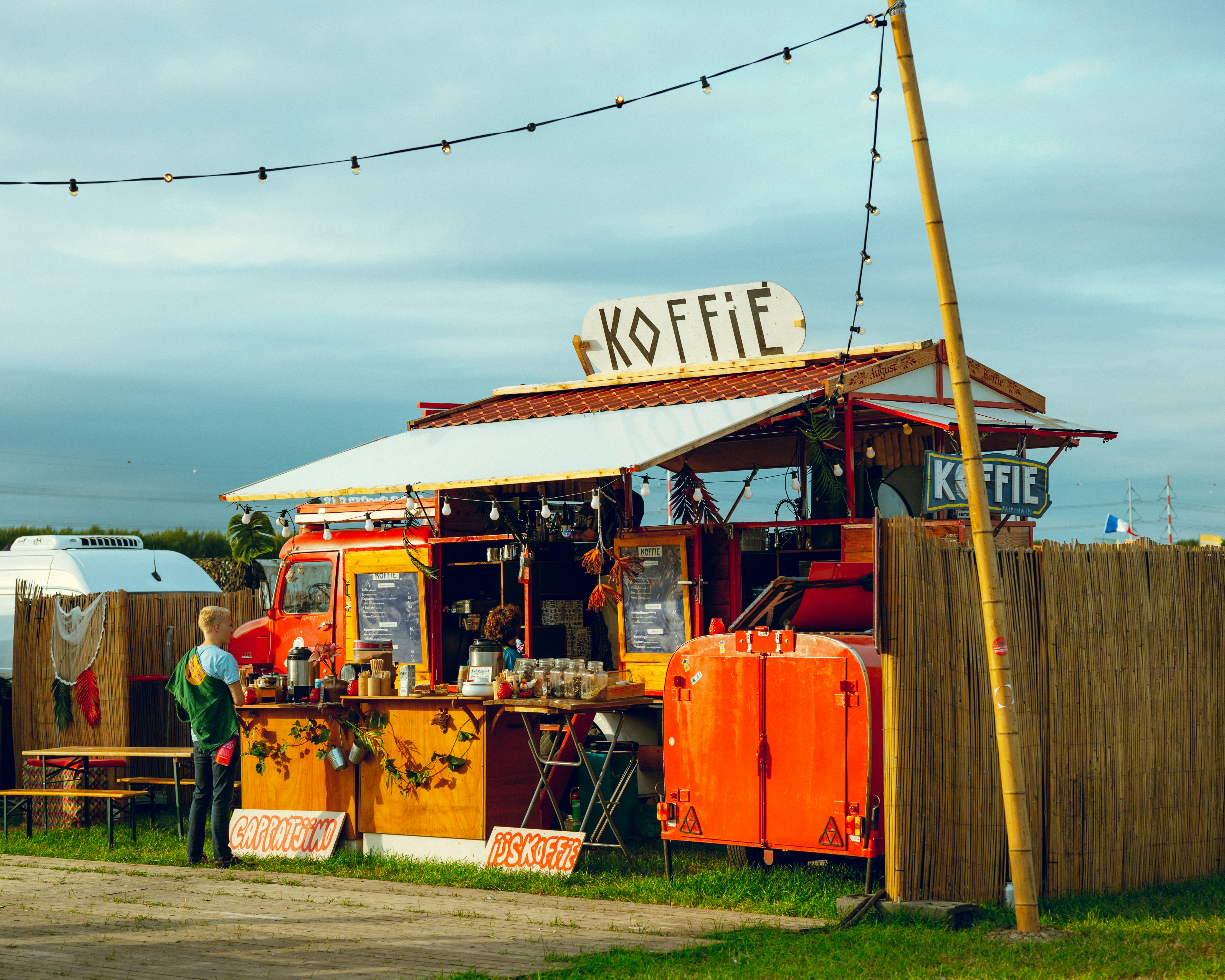 A bright orange food truck selling coffee with a "Koffie" sign on top.