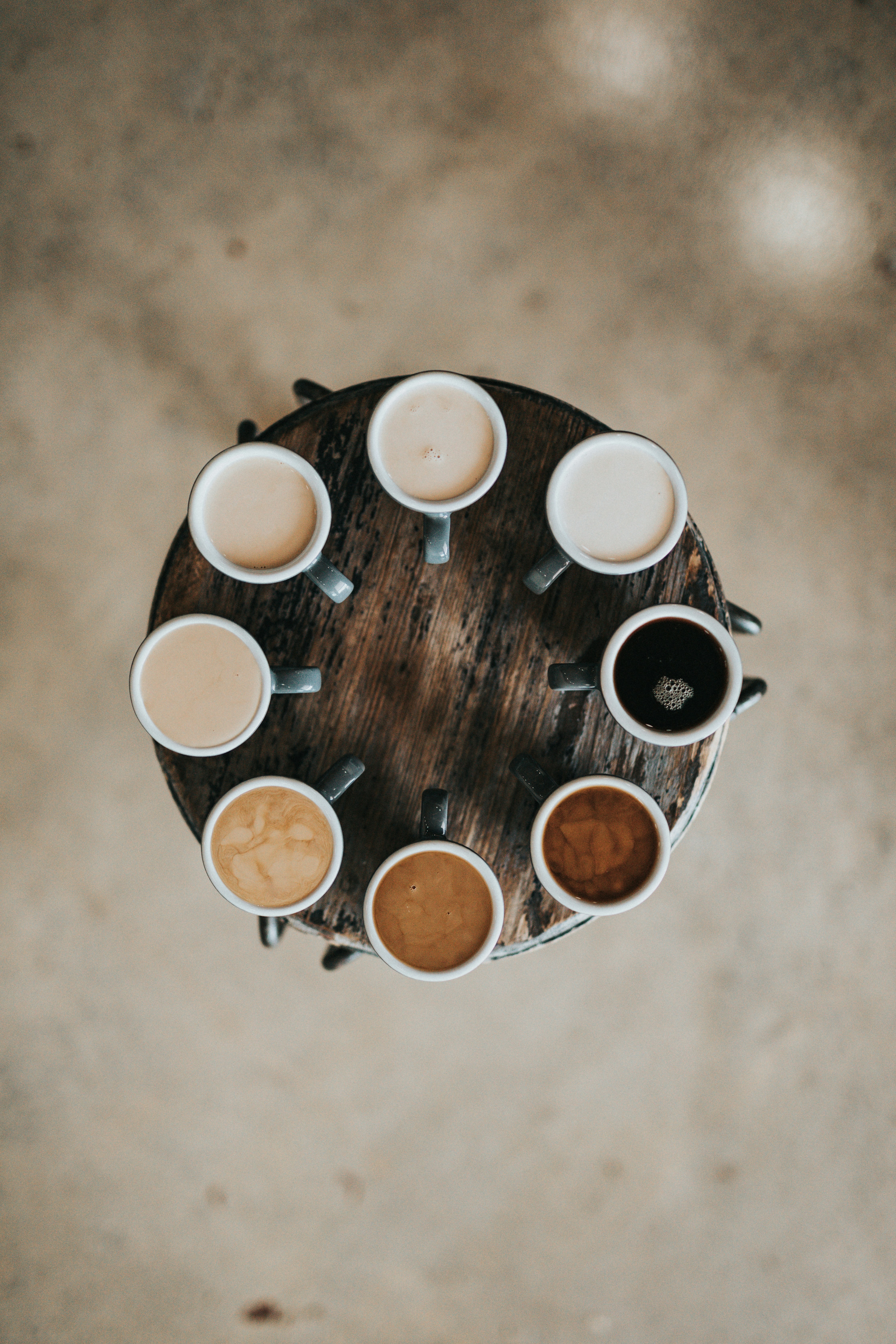A ring of eight cups of coffee in different shades from black to white.