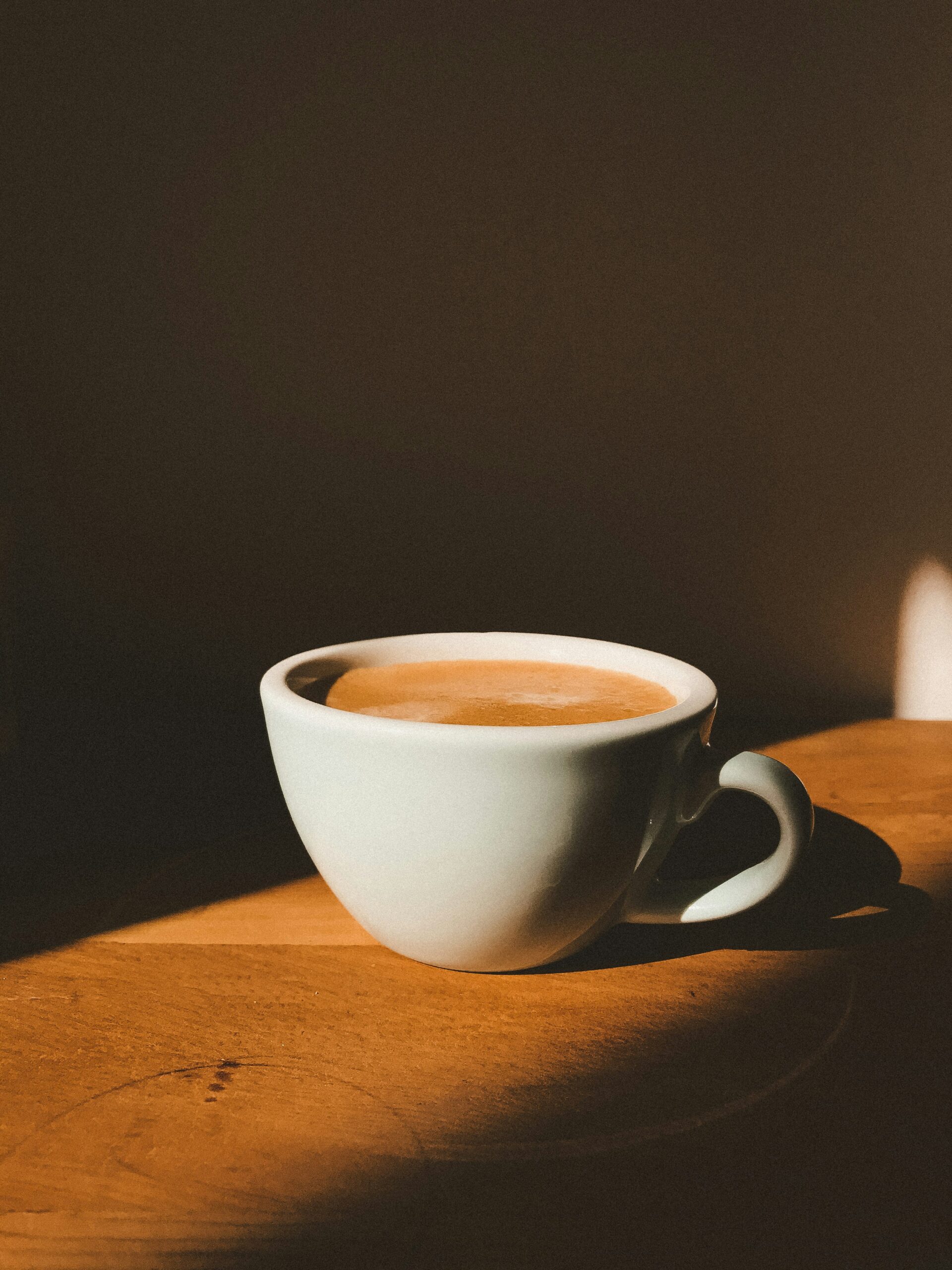 A cup of black coffee on a counter, illuminated by a sunbeam